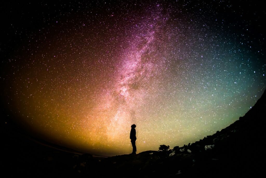 A silhouette of a person looking up at an awesome night sky in contemplation, gaining perspective on life